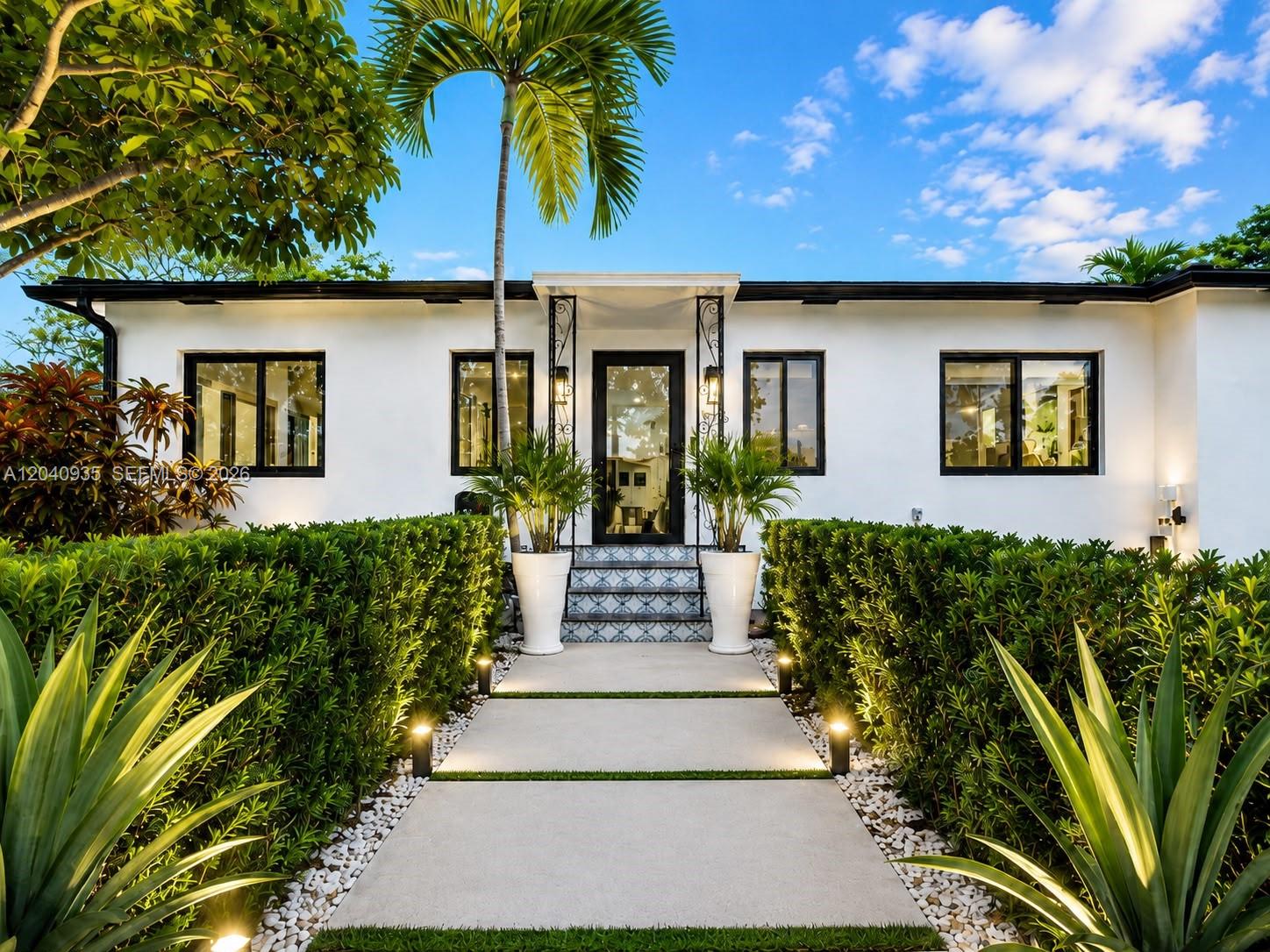 A white house with black window frames features a landscaped walkway leading to the front door — 375 SW 32nd Rd, Miami FL 33129, MIAMI, FL