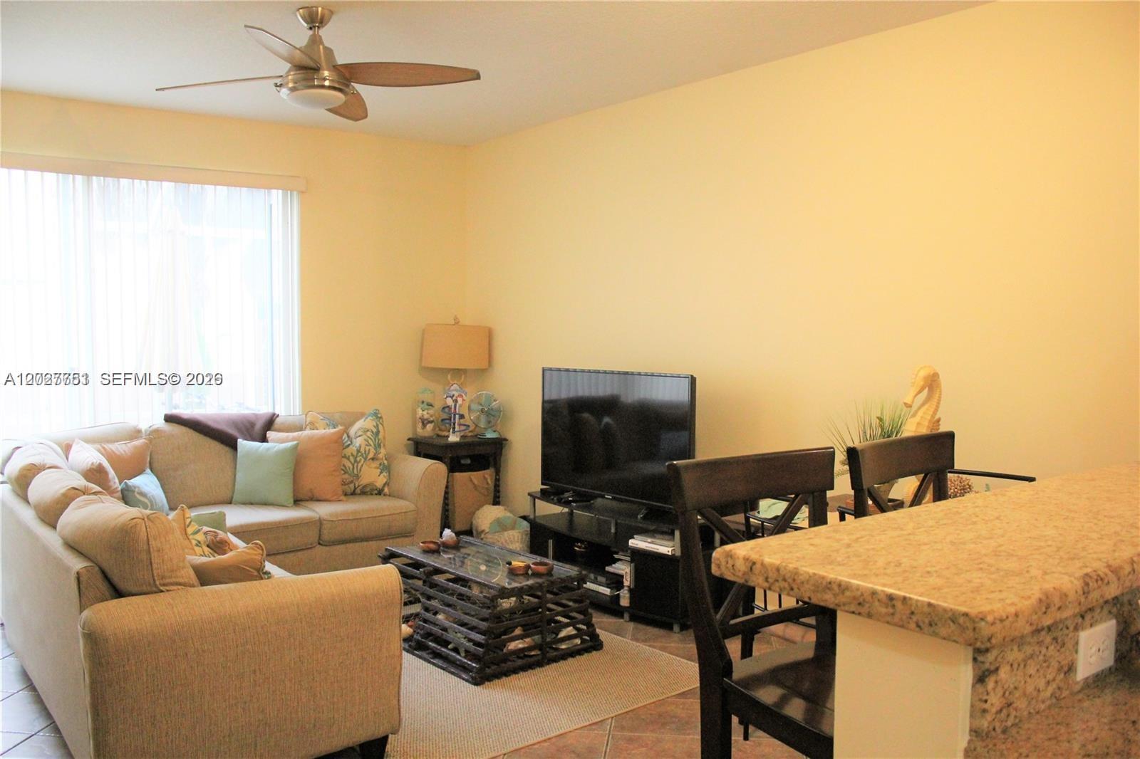 A living room features a beige sofa, a glass-topped coffee table, and a television stand — 3677 San Simeon Cir # 3677, Weston FL 33331, WESTON, FL