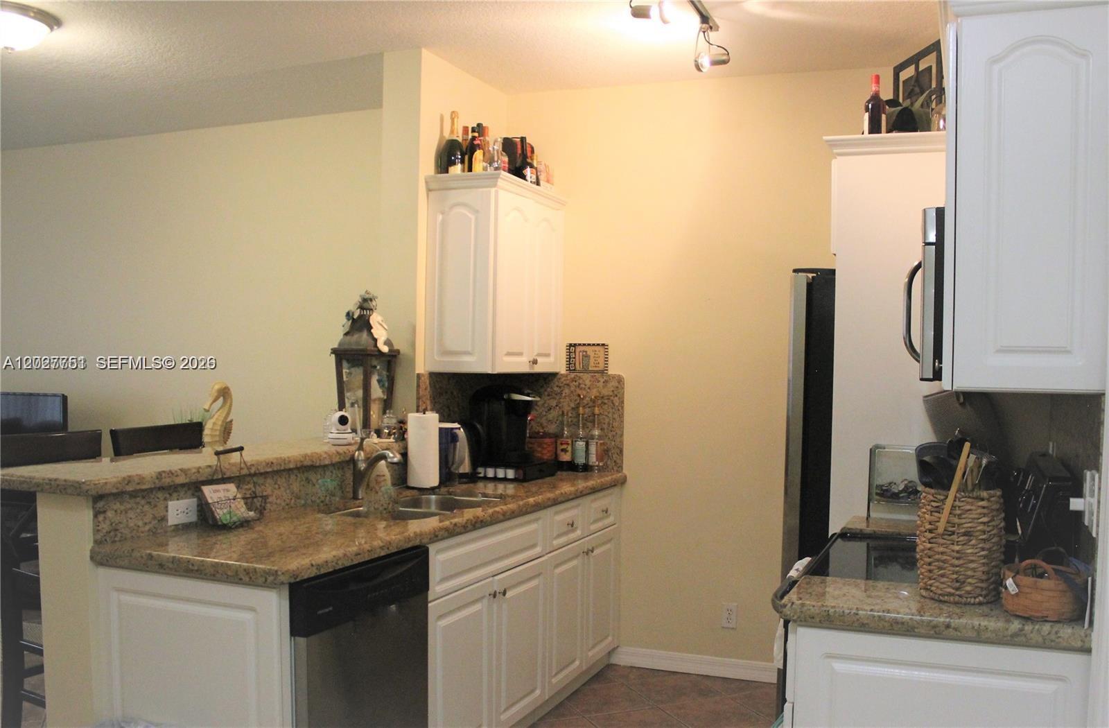 A kitchen features white cabinets, granite countertops, a stainless steel dishwasher, and a breakfast bar — 3677 San Simeon Cir # 3677, Weston FL 33331, WESTON, FL