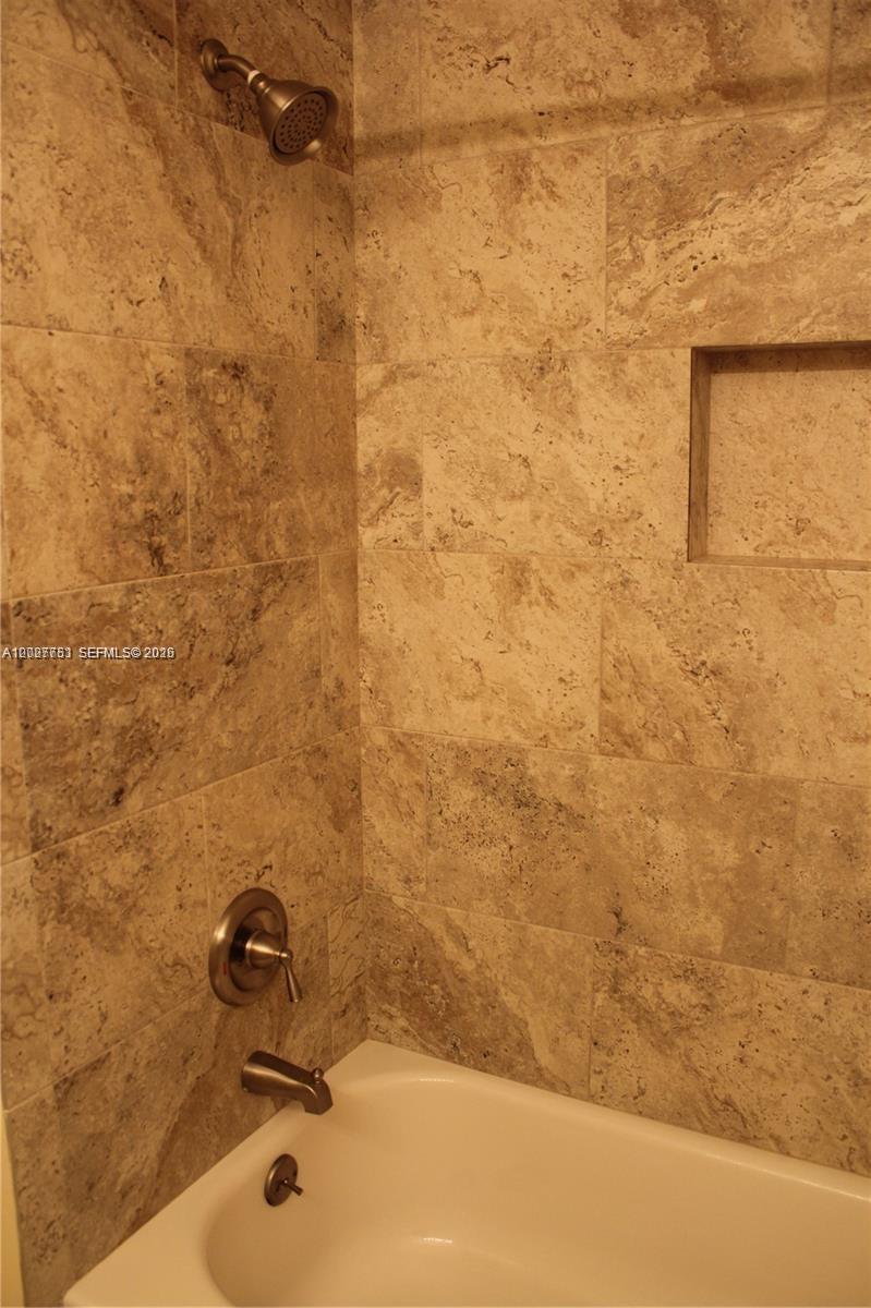 A bathtub with a shower head and a recessed wall niche tiled in beige stone — 3677 San Simeon Cir # 3677, Weston FL 33331, WESTON, FL