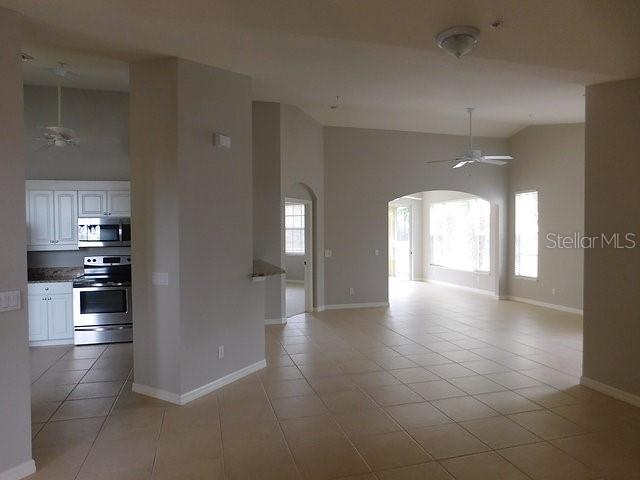 A kitchen with white cabinets and stainless steel appliances opens into a tiled living area — 1669 MONARCH DRIVE UNIT 204, VENICE, FL