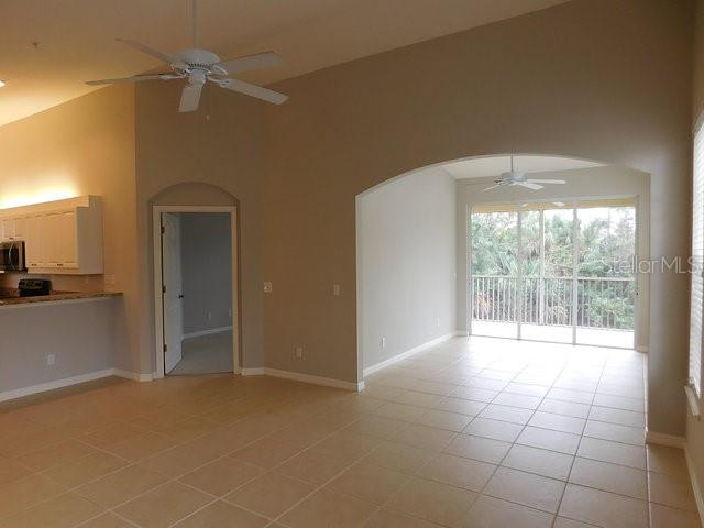 A living area with tile floors, a ceiling fan, and an arched entryway to a balcony — 1669 MONARCH DRIVE UNIT 204, VENICE, FL