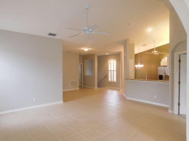 An open-concept living area features light tile flooring, a ceiling fan, and a kitchen island — 1669 MONARCH DRIVE UNIT 204, VENICE, FL
