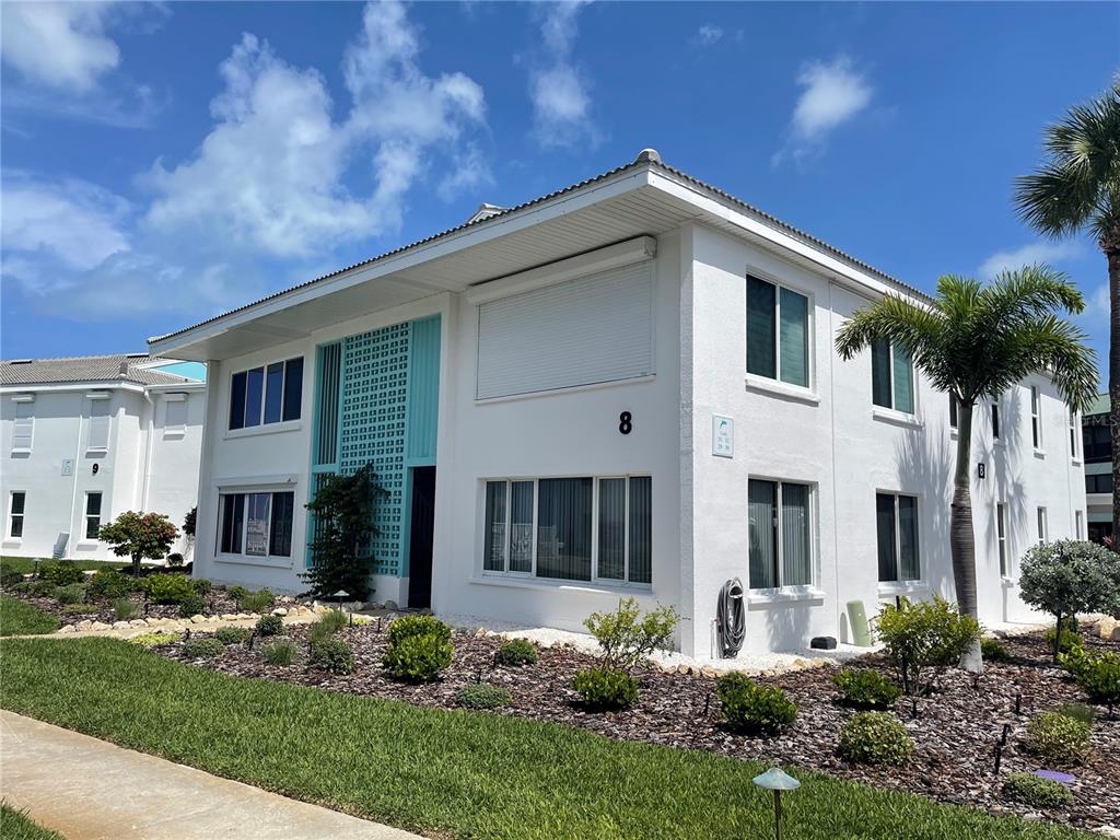 A two-story white apartment building with a teal decorative screen and a palm tree — 5400 GULF DRIVE UNIT 32, BRADENTON BEACH, FL