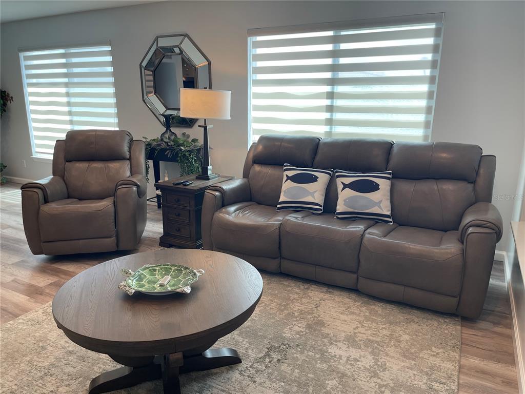 A living room features a leather sofa, matching recliner, round coffee table, and window blinds — 5400 GULF DRIVE UNIT 32, BRADENTON BEACH, FL