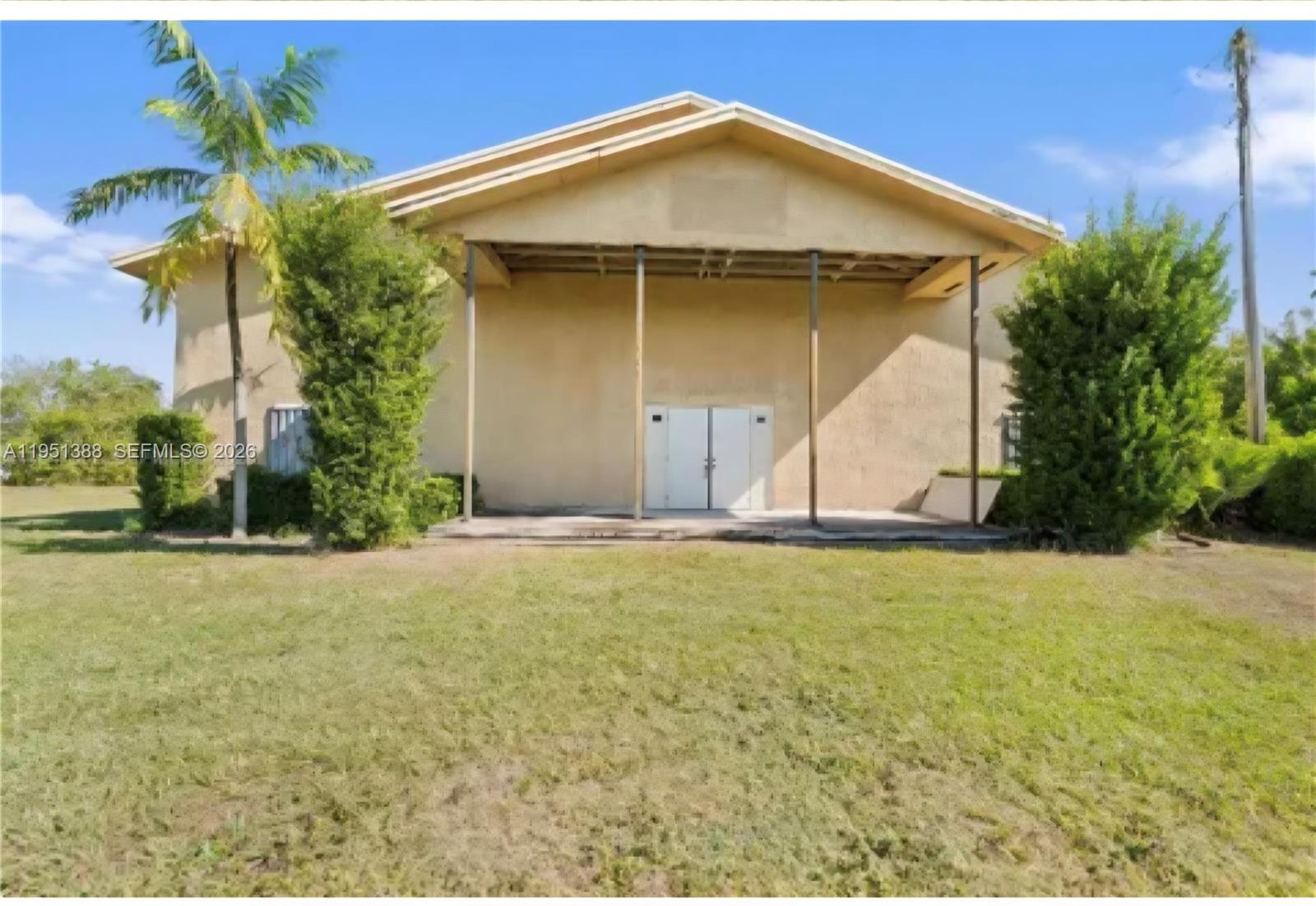 A tan building with a covered porch and double doors stands on a grassy lot — 21571 SW 110th Ave, Miami FL 33189, MIAMI, FL