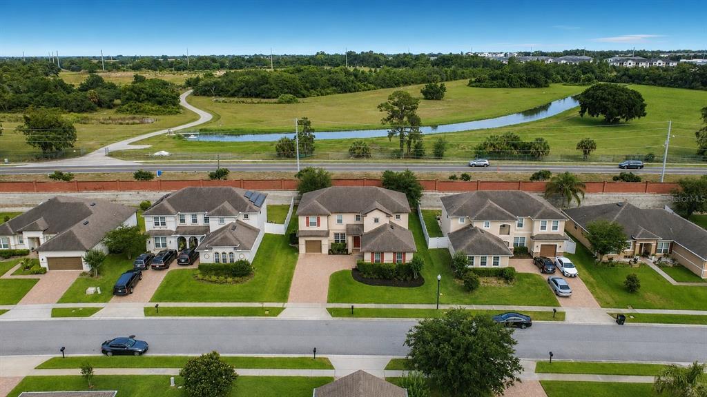 An aerial view shows a row of suburban houses with a brick wall and pond behind — 2771 WESTYN COVE LANE, OCOEE, FL