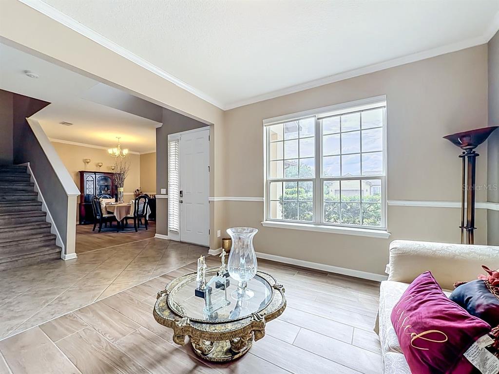 A living room with tile flooring, a glass coffee table, and a view into a dining area — 2771 WESTYN COVE LANE, OCOEE, FL