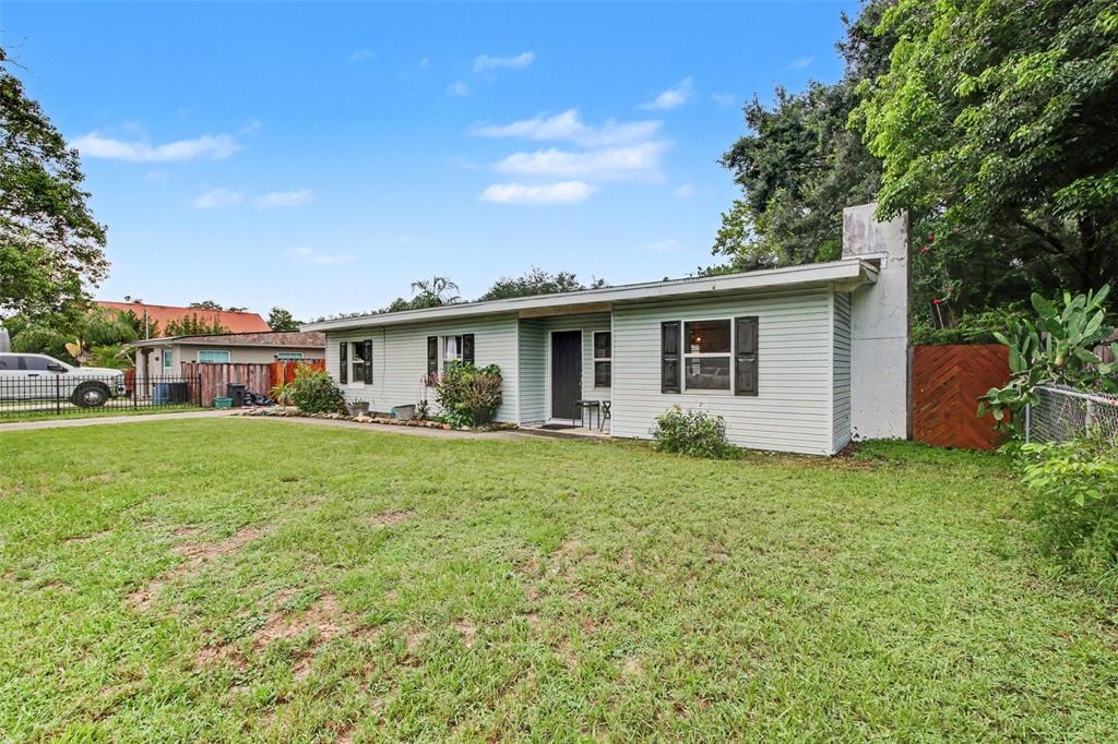 A single-story house with light-colored siding, a front entrance, and a white brick chimney — 231 E 1ST STREET, CHULUOTA, FL