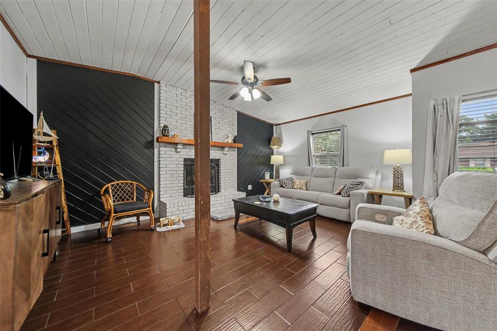 A living room features dark wood floors, a white brick fireplace, and black accent walls — 231 E 1ST STREET, CHULUOTA, FL