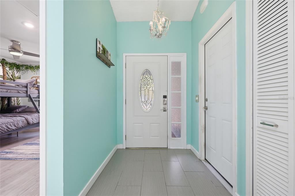 An entryway with light blue walls, gray tile flooring, a white front door, and chandelier — 1014 CONLEY DRIVE, OVIEDO, FL