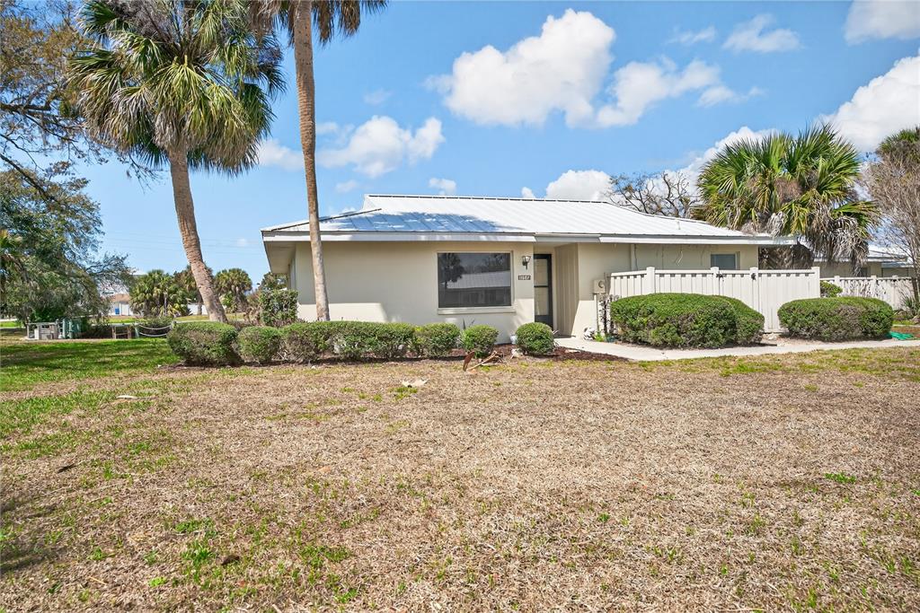 A single-story house with a light-colored exterior, metal roof, and palm trees in the yard — 11607 W KINGFISHER COURT UNIT 198, CRYSTAL RIVER, FL