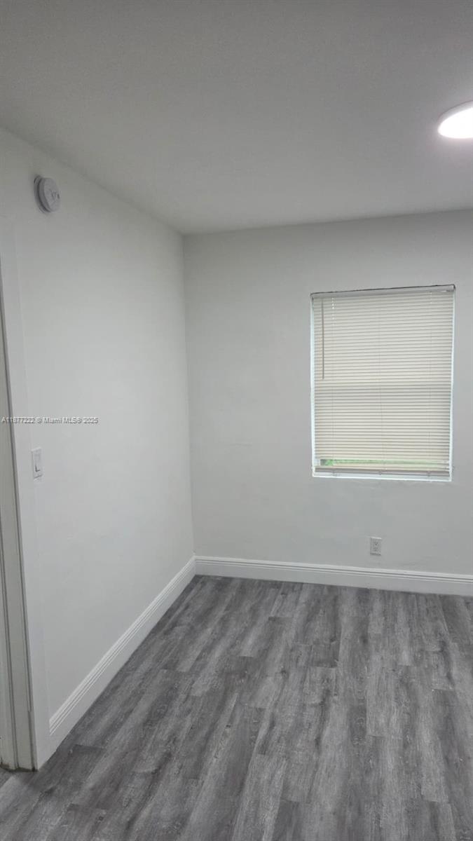 An empty room features light gray walls, white trim, and wood-look flooring with a window — 855 NW 3rd Ter # 6, Dania Beach FL 33004, DANIA BEACH, FL