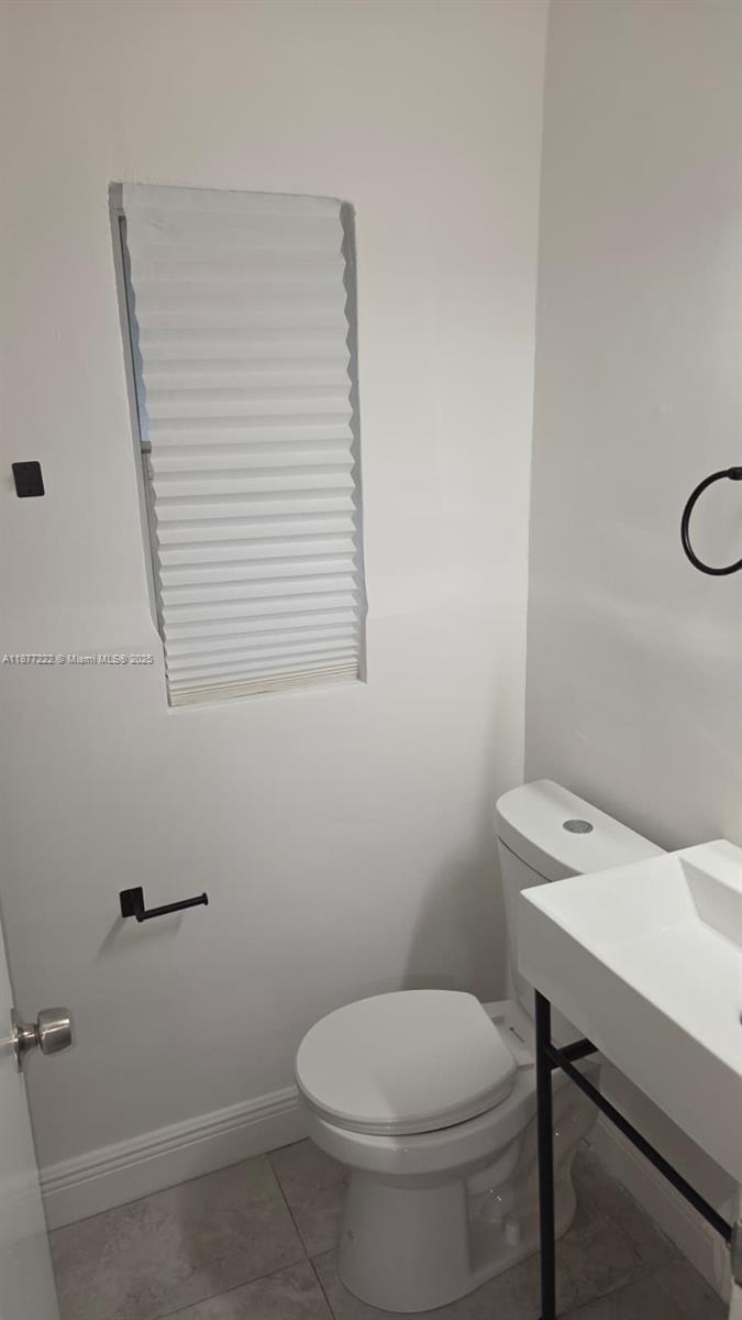 A small bathroom features a white toilet, a pedestal sink, and a window with blinds — 855 NW 3rd Ter # 6, Dania Beach FL 33004, DANIA BEACH, FL