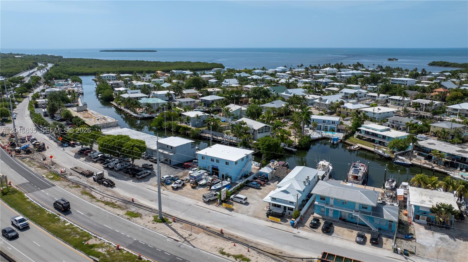 An aerial view shows a coastal neighborhood with houses, canals, and a nearby highway — 90515 Old Hwy, Tavernier FL 33070, TAVERNIER, FL