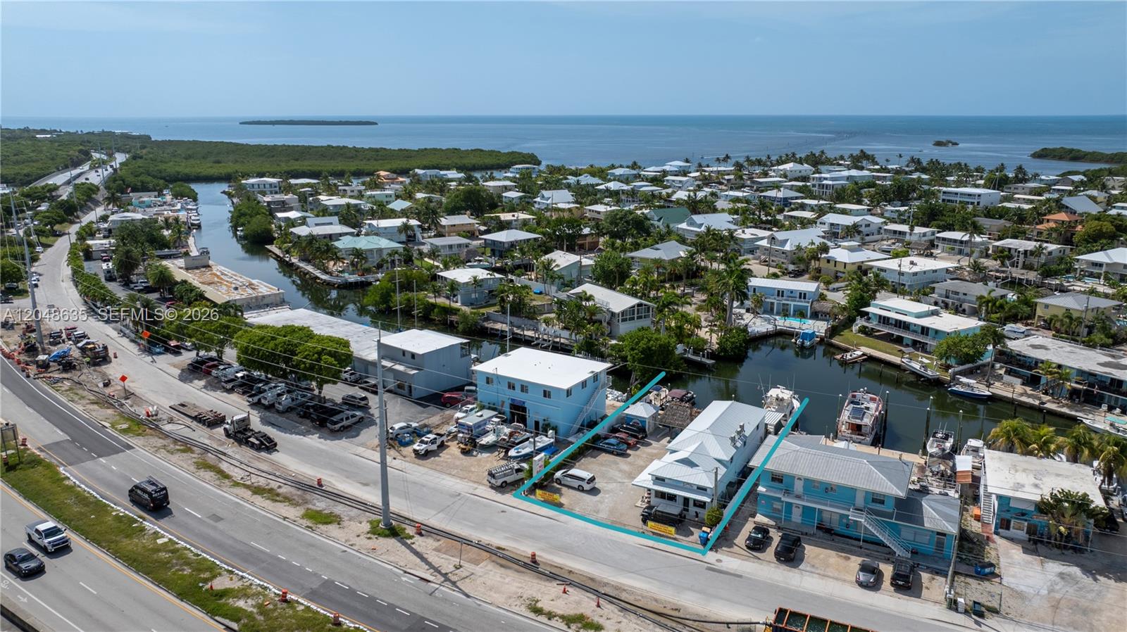 An aerial view shows a waterfront property with a commercial building and boat slips — 90515 Old Hwy, Tavernier FL 33070, TAVERNIER, FL