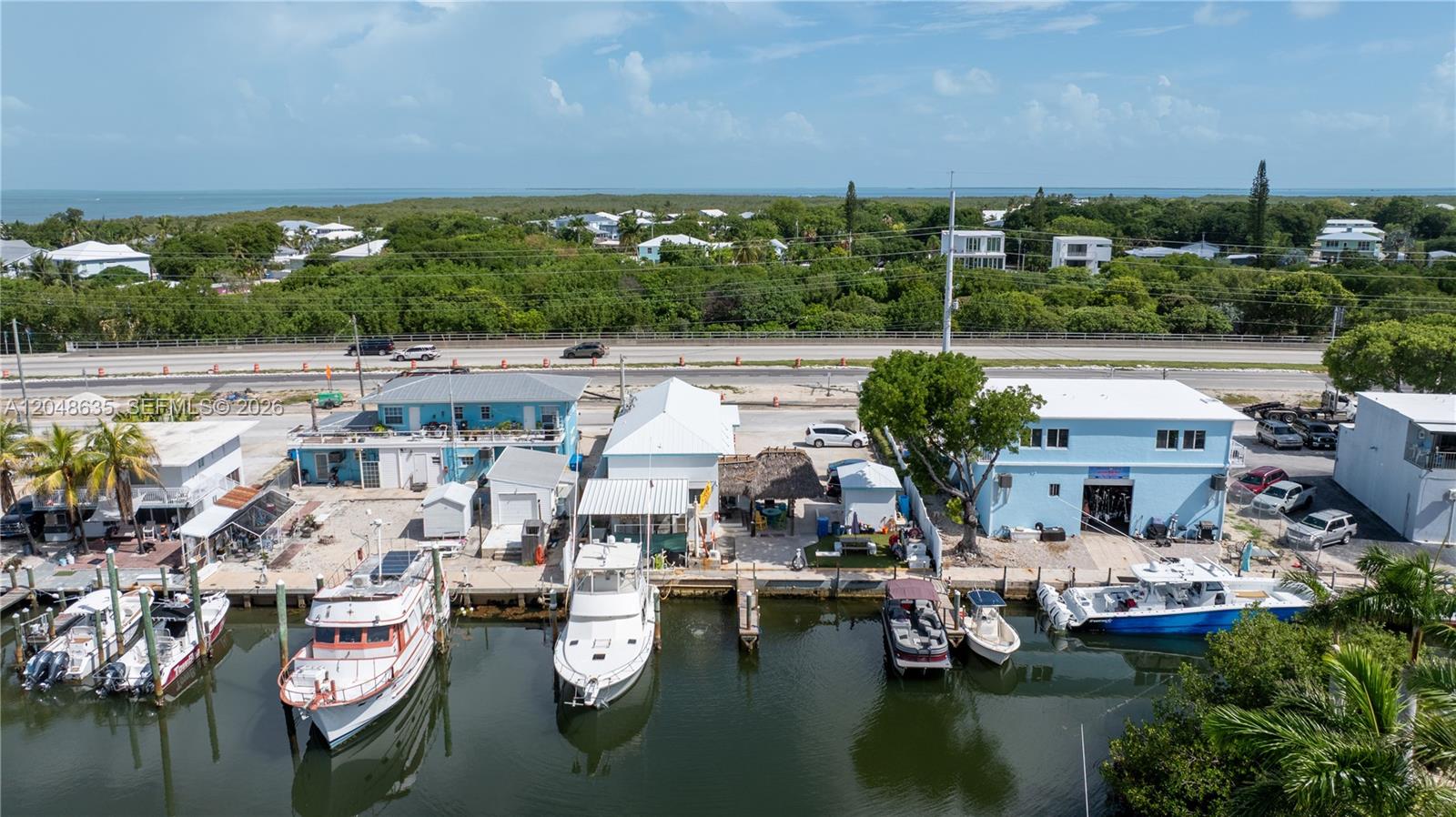 An aerial view shows several waterfront buildings with docked boats along a canal — 90515 Old Hwy, Tavernier FL 33070, TAVERNIER, FL