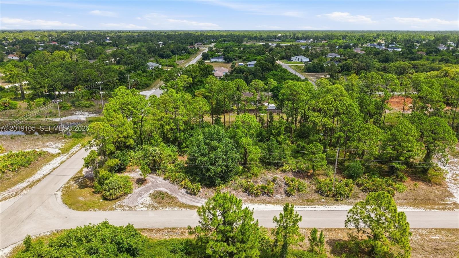 An aerial view shows a wooded, undeveloped lot situated between two paved roads — 911 Sterling, Lehigh Acres FL 33974, LEHIGH ACRES, FL