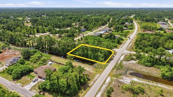 An aerial view shows a vacant, tree-covered rectangular lot outlined in yellow beside a road — 911 Sterling, Lehigh Acres FL 33974, LEHIGH ACRES, FL