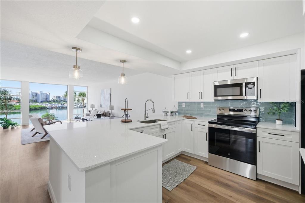 A modern kitchen with white cabinets, quartz countertops, and a view of the water — 7400 SUN ISLAND DRIVE S UNIT 202, SOUTH PASADENA, FL