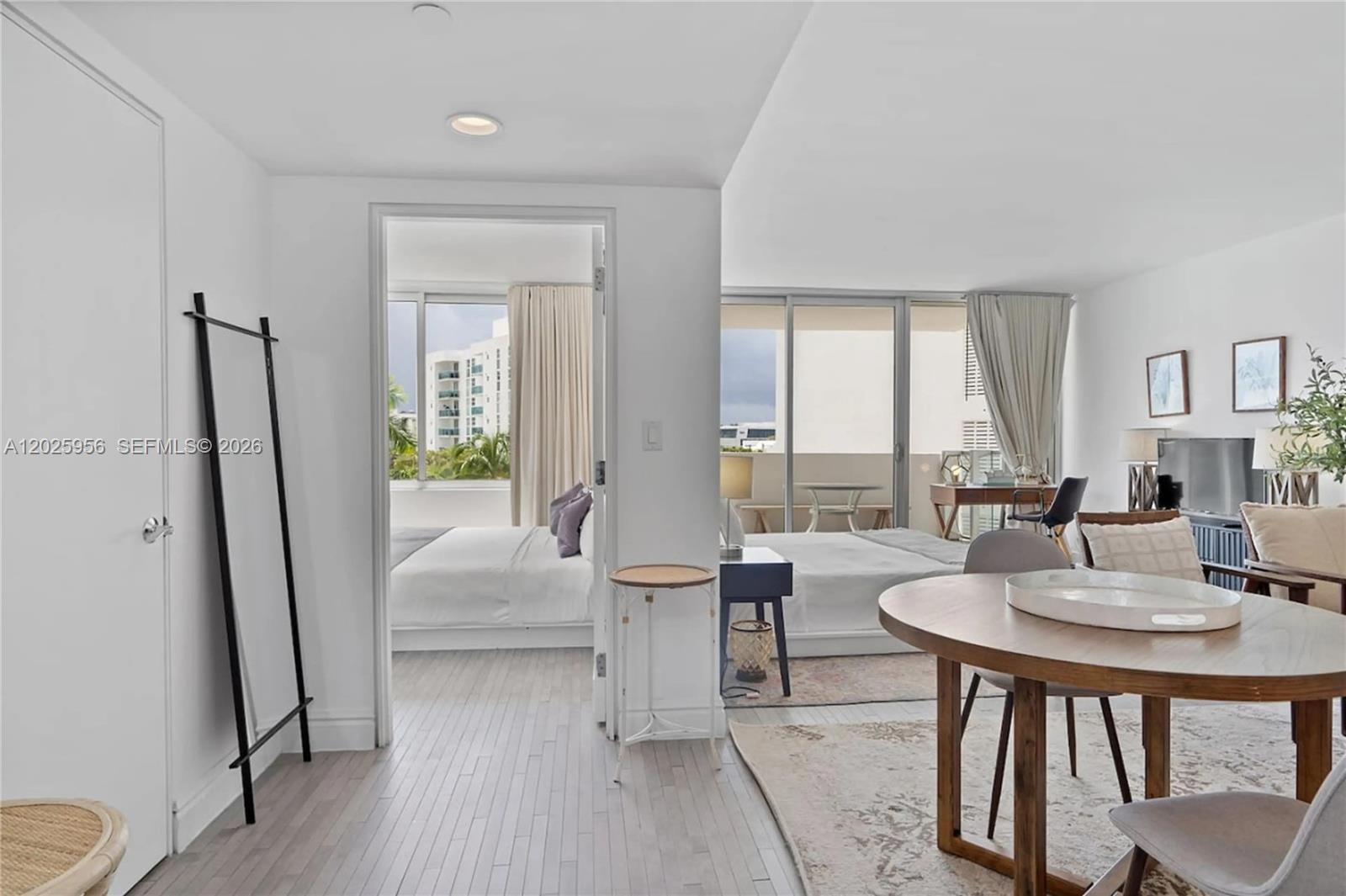 A bright living area with a dining table leads into a bedroom with balcony access — 1100 West Ave # 427, Miami Beach FL 33139, MIAMI BEACH, FL