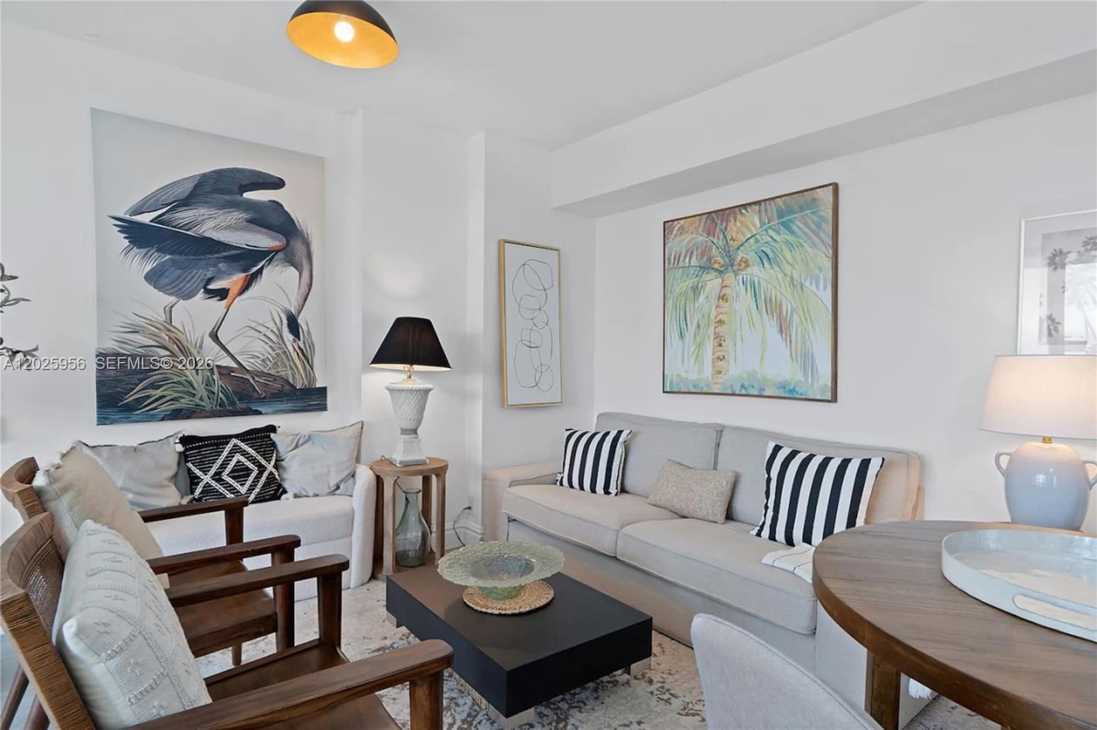 A living room features a beige sofa, wooden armchairs, a coffee table, and wall art — 1100 West Ave # 427, Miami Beach FL 33139, MIAMI BEACH, FL