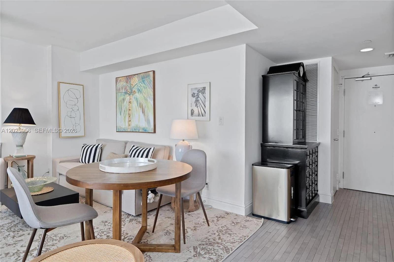 A dining area with a round wooden table sits in front of a living room sofa — 1100 West Ave # 427, Miami Beach FL 33139, MIAMI BEACH, FL