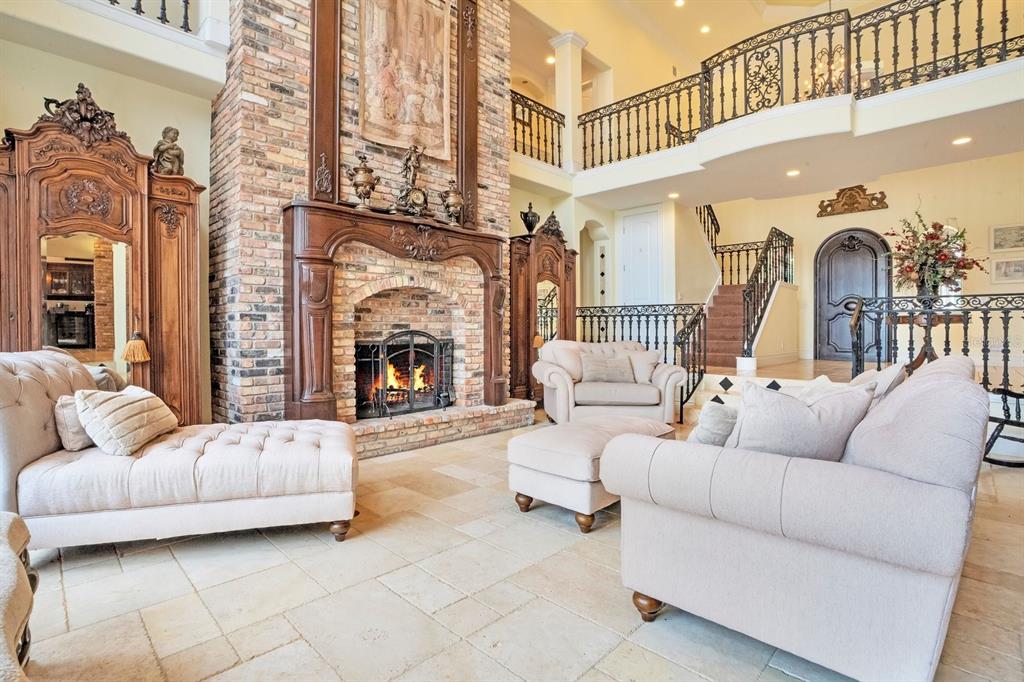 A two-story living room features a large brick fireplace, stone floors, and a balcony railing — 133 VAN FLEET COURT, AUBURNDALE, FL