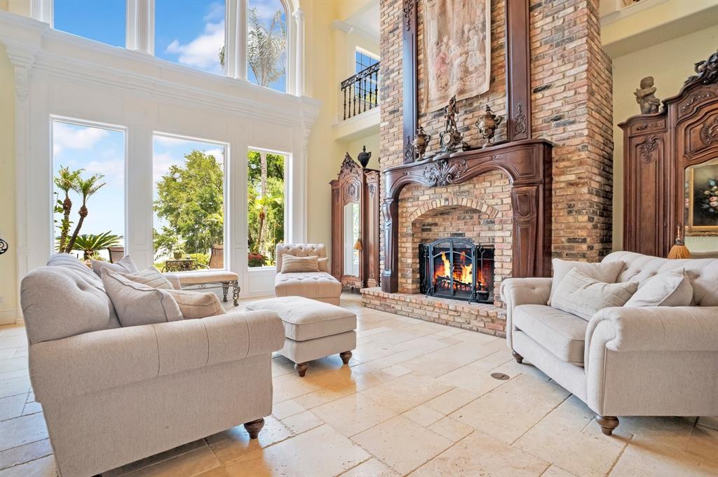A living room features a tall brick fireplace, light-colored sofas, and large floor-to-ceiling windows — 133 VAN FLEET COURT, AUBURNDALE, FL