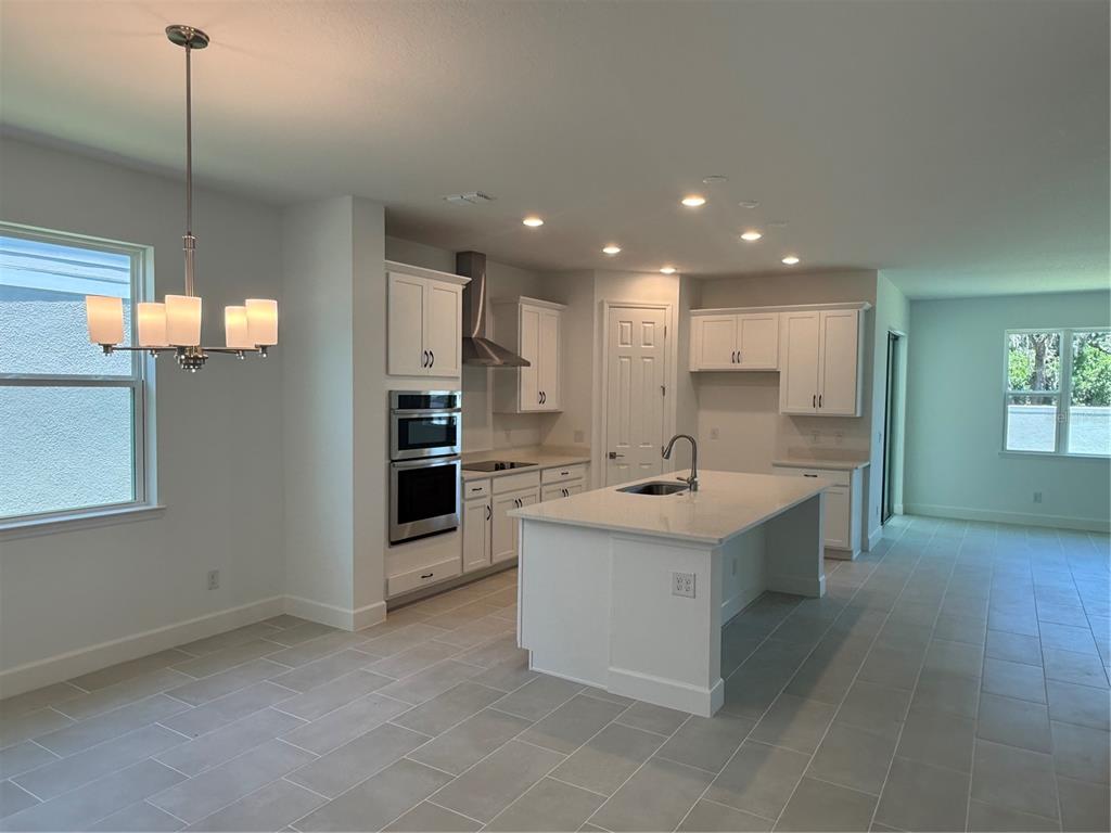 A modern kitchen features white cabinets, stainless steel appliances, a center island, and tile flooring — 2680 CAVANAUGH DRIVE, ORLANDO, FL