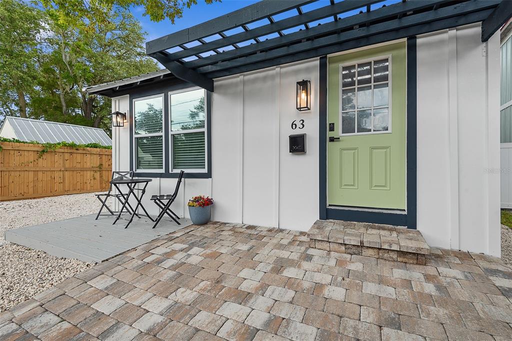 The exterior of a house features a light green door, white siding, and a paver patio — 63 ONEIDA STREET, ST AUGUSTINE, FL