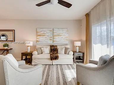 A living room features a white sofa, two armchairs, and two abstract wall art pieces — MIAMI GARDENS, FL