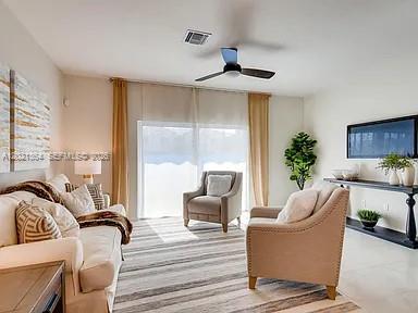 A living room features a beige sofa, an armchair, a ceiling fan, and a television — MIAMI GARDENS, FL