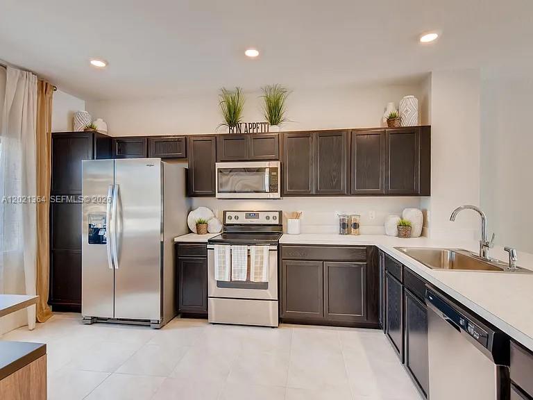 A kitchen features dark wood cabinets, stainless steel appliances, and light-colored countertops — MIAMI GARDENS, FL