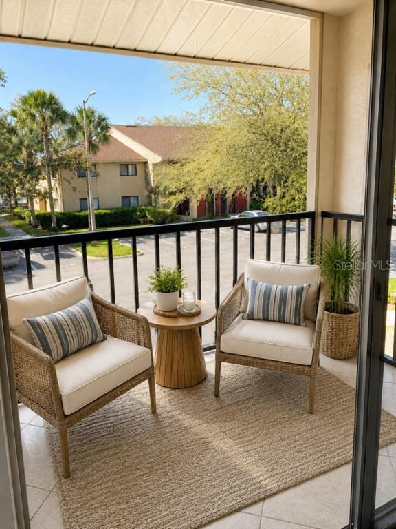 A balcony features two wicker chairs with cushions, a small wooden table, and a rug — 5553 BAYWATER DRIVE, TAMPA, FL