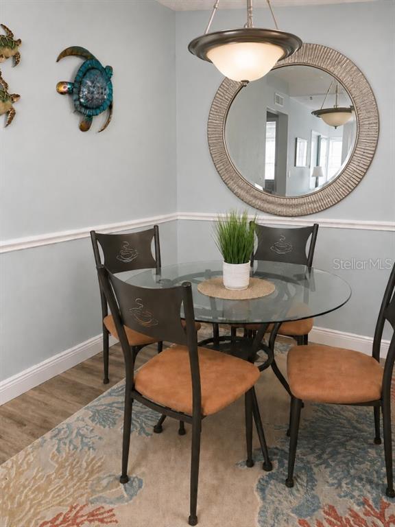 A dining area features a glass-topped table, four chairs, a round mirror, and wall decor — 5553 BAYWATER DRIVE, TAMPA, FL