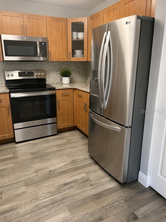 A kitchen features light wood cabinets, stainless steel appliances, and wood-look flooring — 5553 BAYWATER DRIVE, TAMPA, FL
