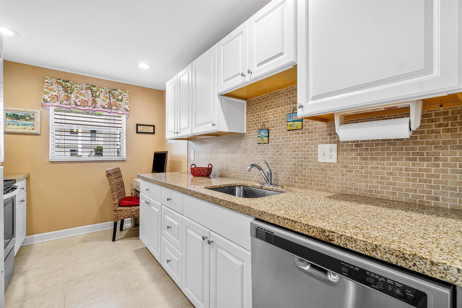 A kitchen features white cabinets, granite countertops, a tiled backsplash, and stainless steel appliances — 2700 SW 22nd Avenue # 1409, Delray Beach FL 33445, DELRAY BEACH, FL