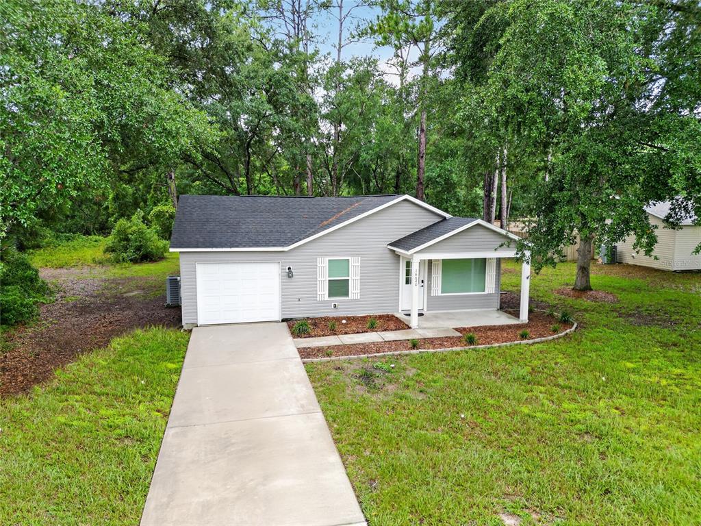 A single-story gray house with a white garage door, a front porch, and a concrete driveway — 16640 SE 59TH PLACE, OCKLAWAHA, FL
