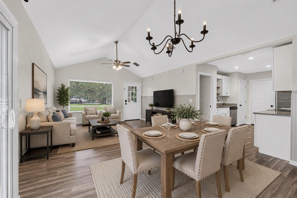 An open-concept living and dining area with vaulted ceilings, wood-look flooring, and a chandelier — 16640 SE 59TH PLACE, OCKLAWAHA, FL