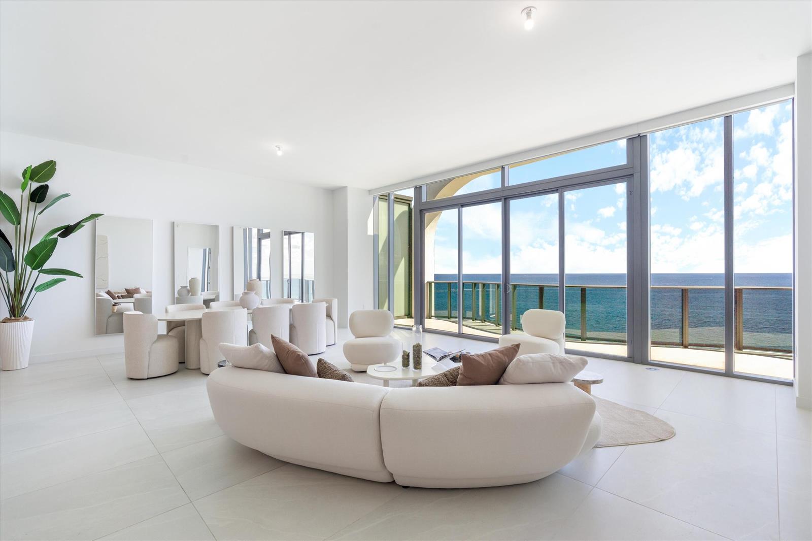 A bright, open-plan living and dining area features white furniture, tiled floors, and floor-to-ceiling windows — 900 N Ocean Boulevard, Pompano Beach FL 33062, POMPANO BEACH, FL