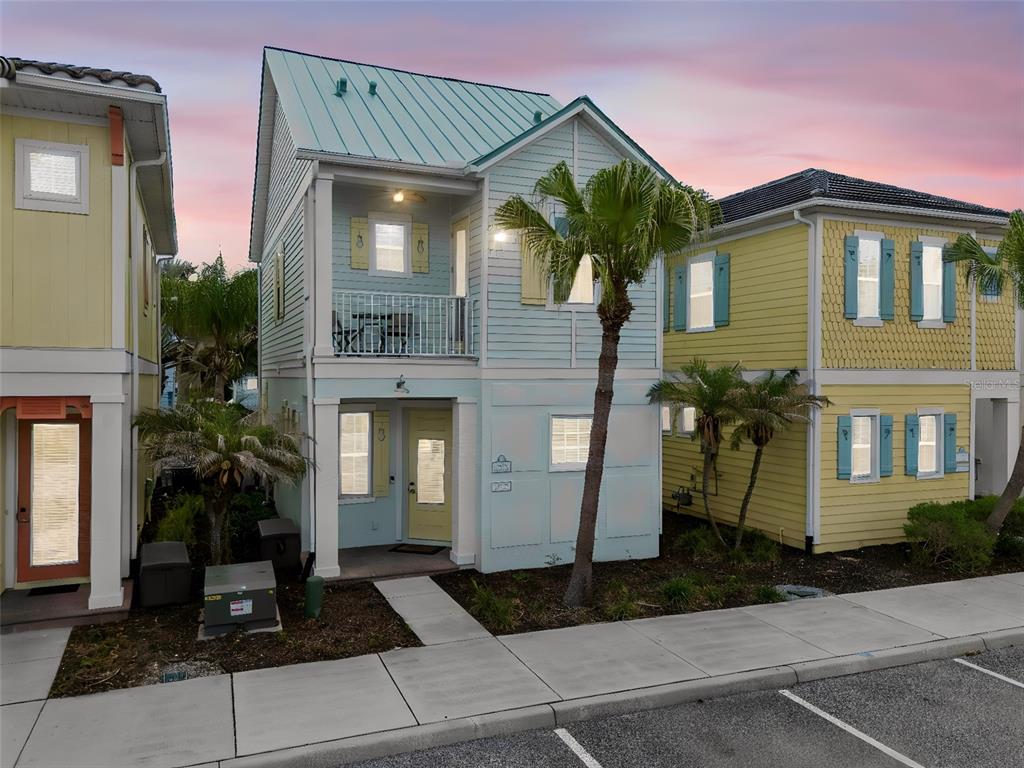 A light green two-story house with a metal roof and a palm tree in front — 3009 SEA PLANE LANE, KISSIMMEE, FL