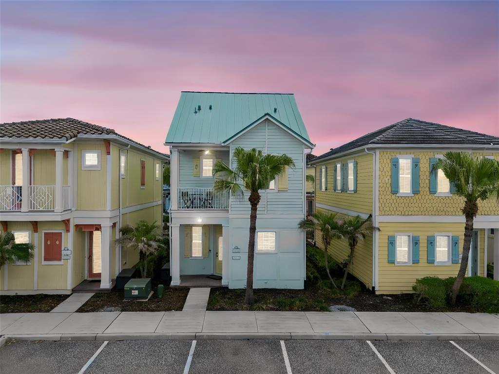 A kitchen with white cabinets and stainless steel appliances opens into a bright living area — 3009 SEA PLANE LANE, KISSIMMEE, FL