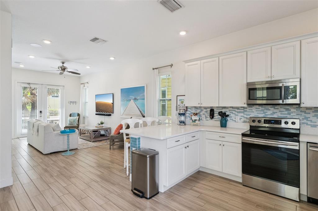A kitchen features white cabinets, stainless steel appliances, a breakfast bar, and light wood flooring — 3009 SEA PLANE LANE, KISSIMMEE, FL