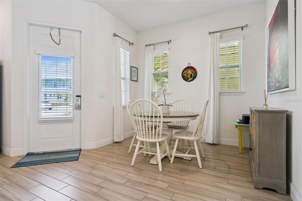 A dining area features a round wooden table, four white chairs, and light wood-look flooring — 3009 SEA PLANE LANE, KISSIMMEE, FL