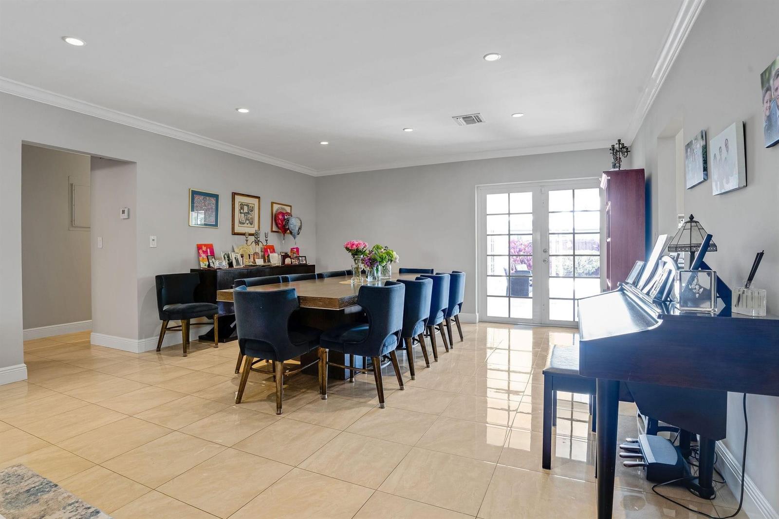 A dining room with a long wooden table, blue upholstered chairs, and beige tile flooring — 4000 N 36th Avenue, Hollywood FL 33021, HOLLYWOOD, FL