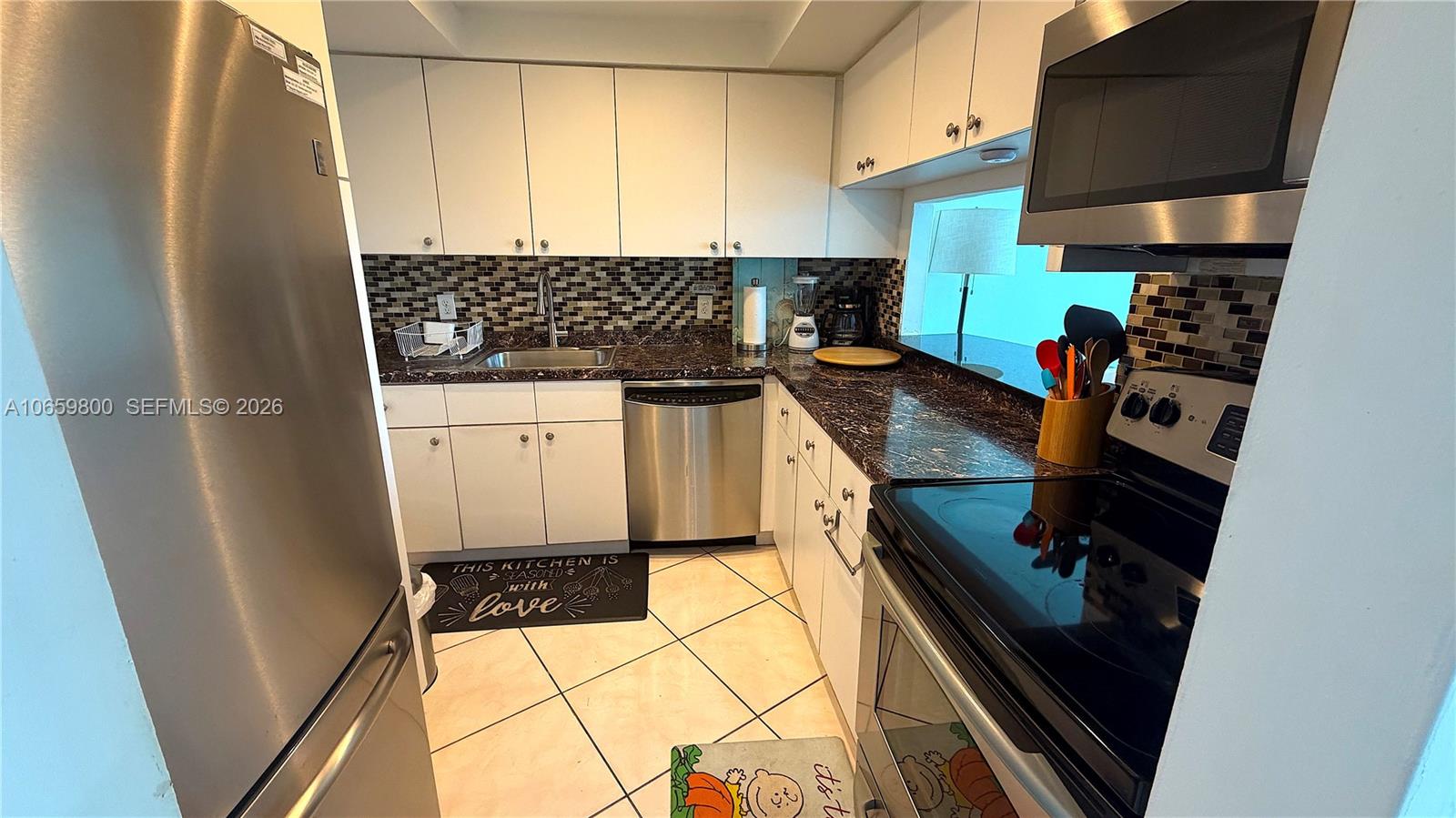 A kitchen features stainless steel appliances, white cabinets, dark granite countertops, and a tiled backsplash — 3505 S Ocean Dr # 1403, Hollywood FL 33019, HOLLYWOOD, FL