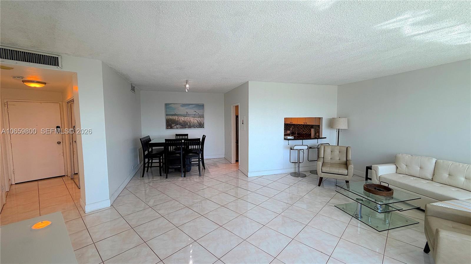 An open-concept living and dining area features white tile floors, a kitchen pass-through, and furniture — 3505 S Ocean Dr # 1403, Hollywood FL 33019, HOLLYWOOD, FL