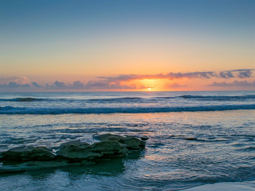 A sunrise over the ocean with rock formations visible in the foreground water — 100 TEQUESTA COURT, PALM COAST, FL
