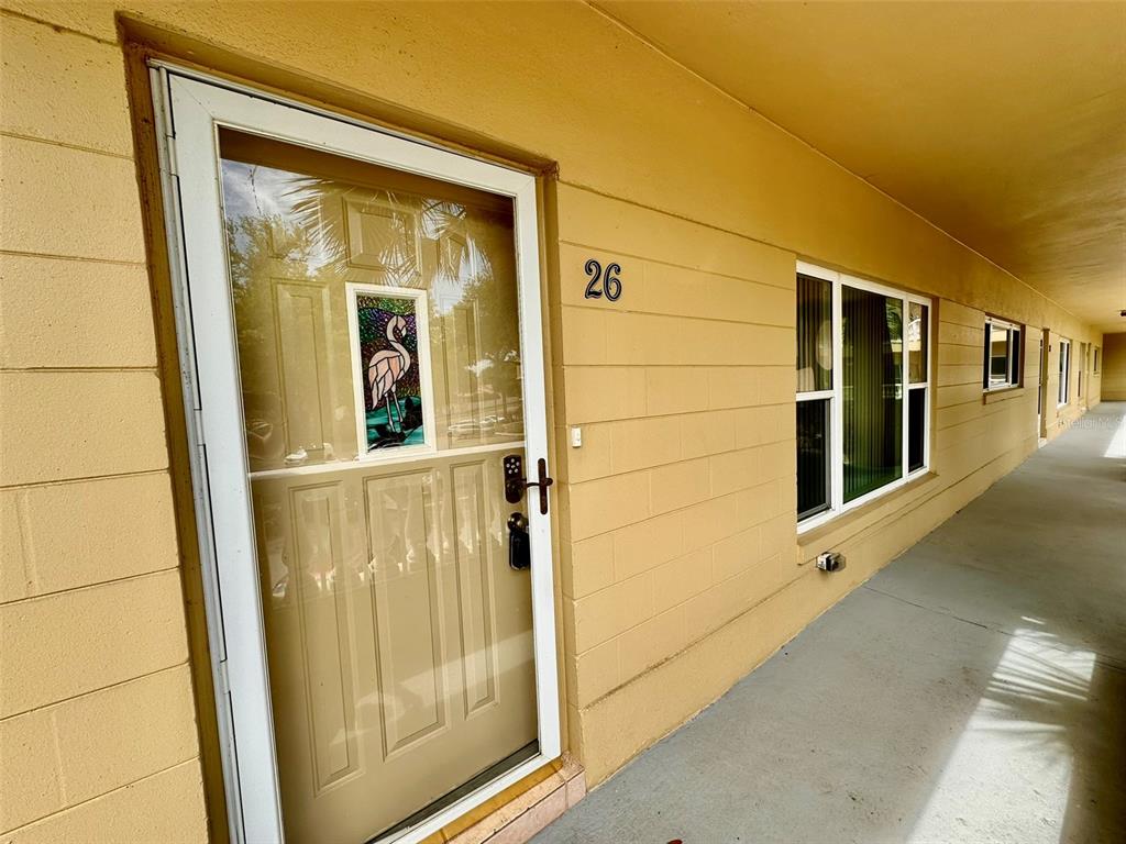 A tan exterior wall features a front door with a flamingo insert and number 26 — 2220 SPANISH DRIVE UNIT 26, CLEARWATER, FL